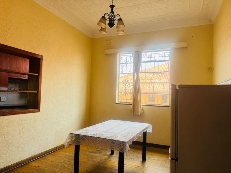 Dining area featuring original timber flooring, ornate ceiling detail, and built-in wall shelving, offering a classic foundation for modern updates.