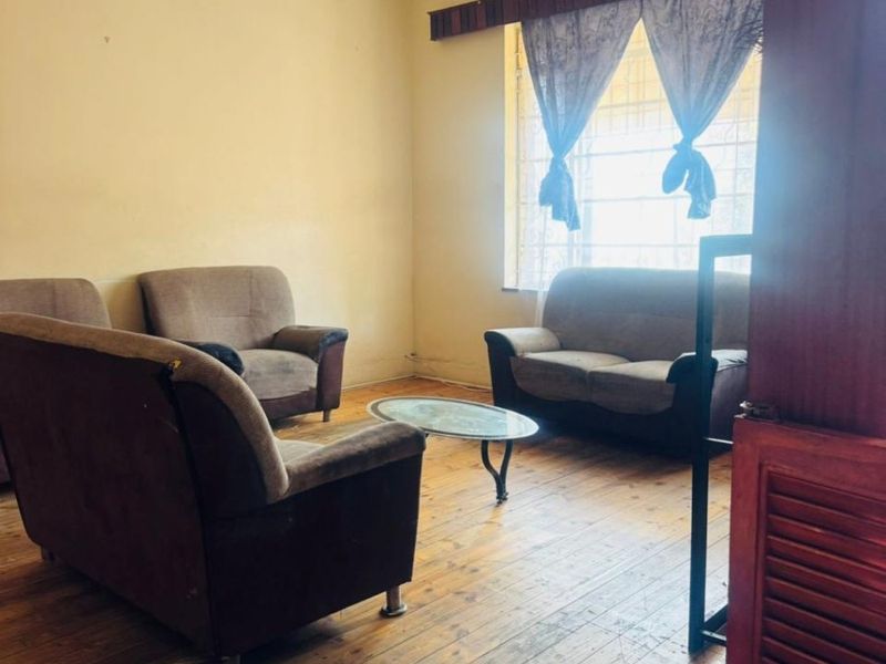 A living room featuring original hardwood flooring, ornate ceiling detailing, and coving, offering a classic foundation for modern updates.