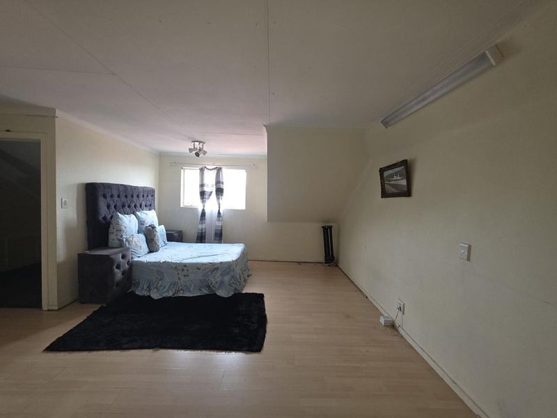 Spacious bedroom featuring laminate flooring and basic lighting fixtures, offering a blank canvas for potential interior design updates.
