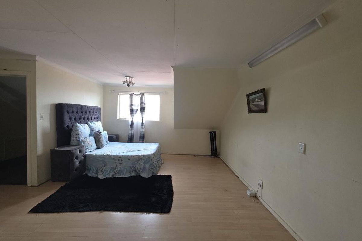 Spacious bedroom featuring laminate flooring and basic lighting fixtures, offering a blank canvas for potential interior design updates.