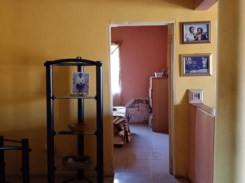 A hallway area featuring tiled flooring and a structural column, providing access to adjacent rooms with visible wall surface wear.