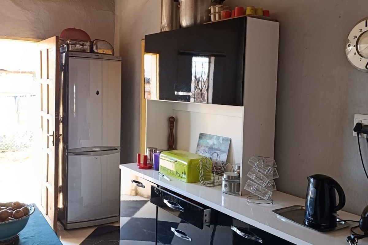 A functional kitchen area featuring built-in cabinetry, a countertop, and direct access to the exterior through a doorway.