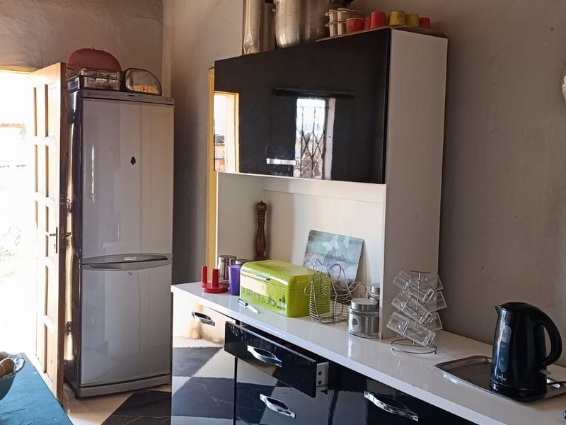 A functional kitchen area featuring built-in cabinetry, a countertop, and direct access to the exterior through a doorway.