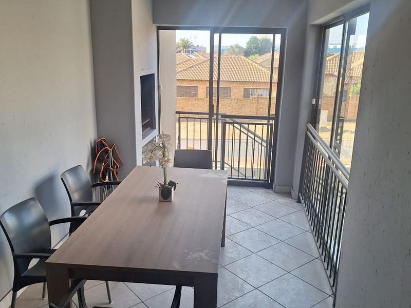 Covered balcony featuring tiled flooring, a built-in braai, and metal balustrades, offering a functional outdoor entertainment space.