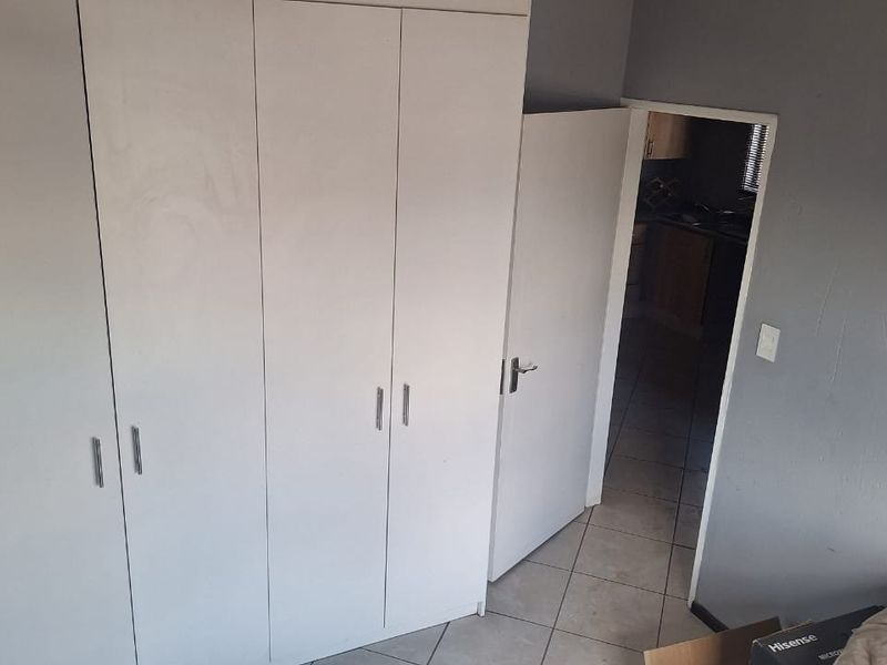 A bedroom featuring built-in cupboards and tiled flooring, with a doorway leading to an adjacent room.