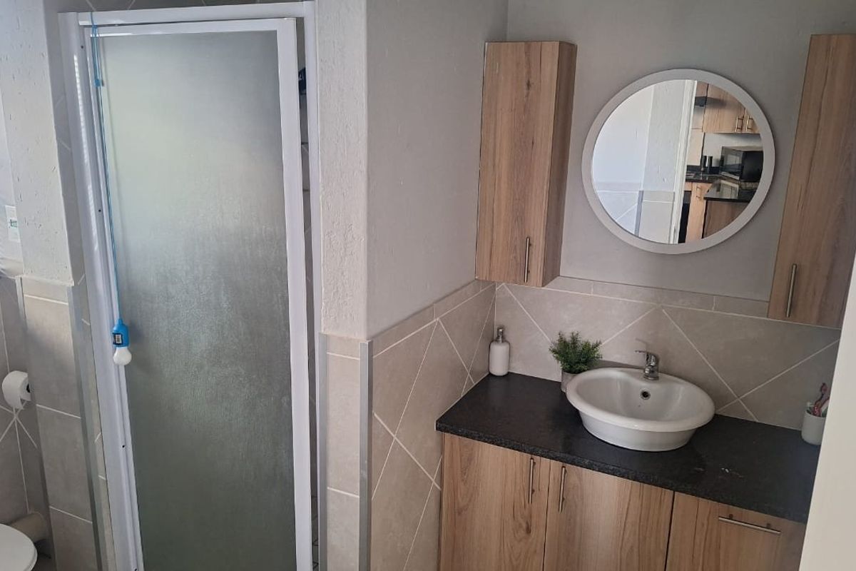 A well-maintained bathroom featuring a shower enclosure, a modern vanity with a vessel sink, and ample wall-mounted storage cabinetry.