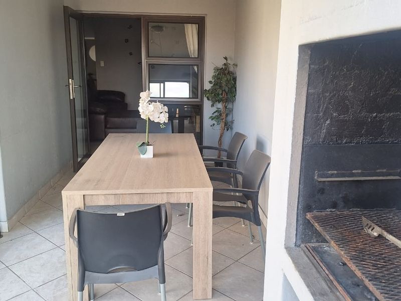 Covered balcony featuring a built-in braai, tiled flooring, and direct access to the interior living area through sliding doors.