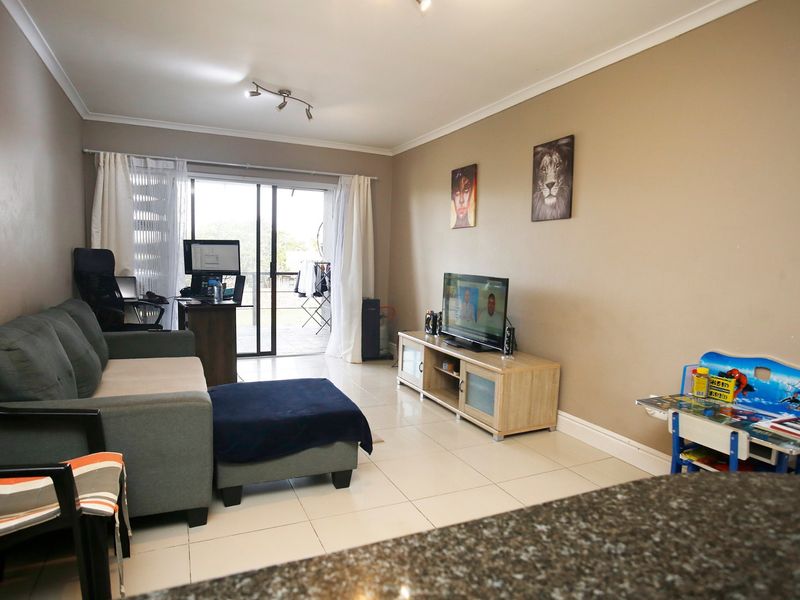 A well-lit living room featuring tiled flooring and a sliding glass door that provides access to an outdoor patio area.