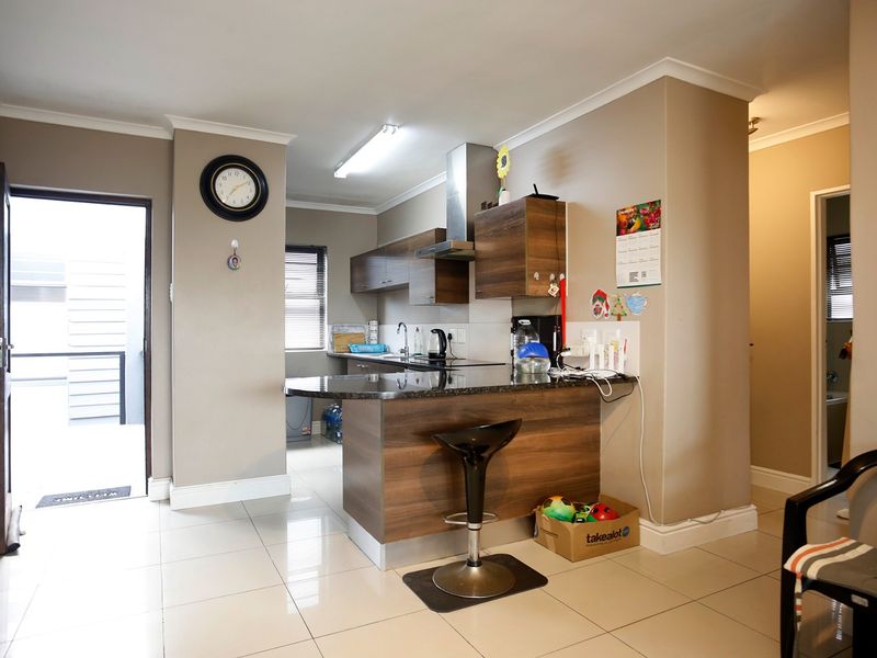 Open-plan kitchen featuring modern wood-finish cabinetry, granite countertops, and a breakfast nook, seamlessly integrated with the living area and exterior access.