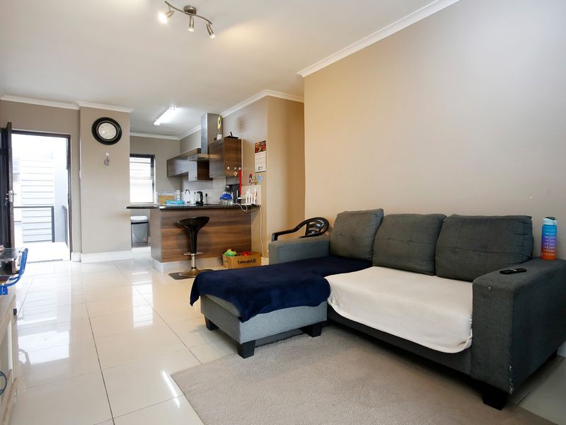 Open plan living area featuring tiled flooring and a functional kitchen with built-in cabinetry, island, and extractor fan.