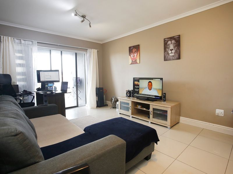 A functional living room featuring tiled flooring and a sliding glass door that provides access to the outdoor area.