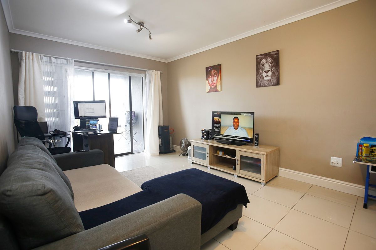 A functional living room featuring tiled flooring and a sliding glass door that provides access to the outdoor area.