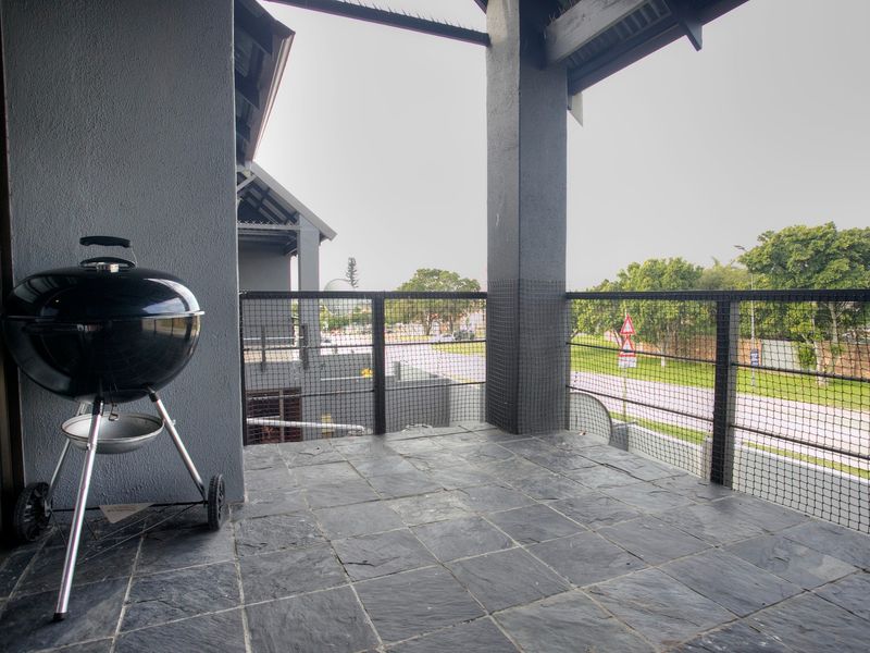 A covered balcony featuring slate tile flooring and a metal balustrade, offering an outdoor space suitable for relaxation.
