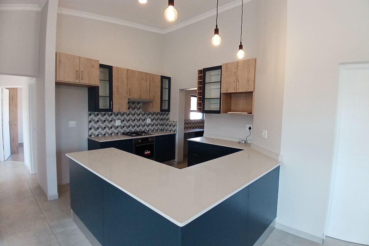 Modern kitchen featuring U-shaped stone countertops, two-tone cabinetry, built-in oven and gas hob, and stylish pendant lighting in an open-plan layout.