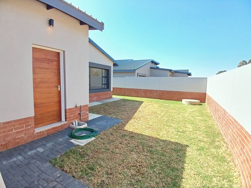 A private rear garden featuring a paved walkway, a timber door entrance, and secure brick boundary walls.