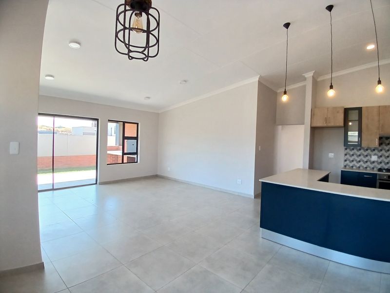 Spacious open-plan living area featuring a modern kitchen with stone countertops, built-in appliances, and large sliding doors leading to the exterior.