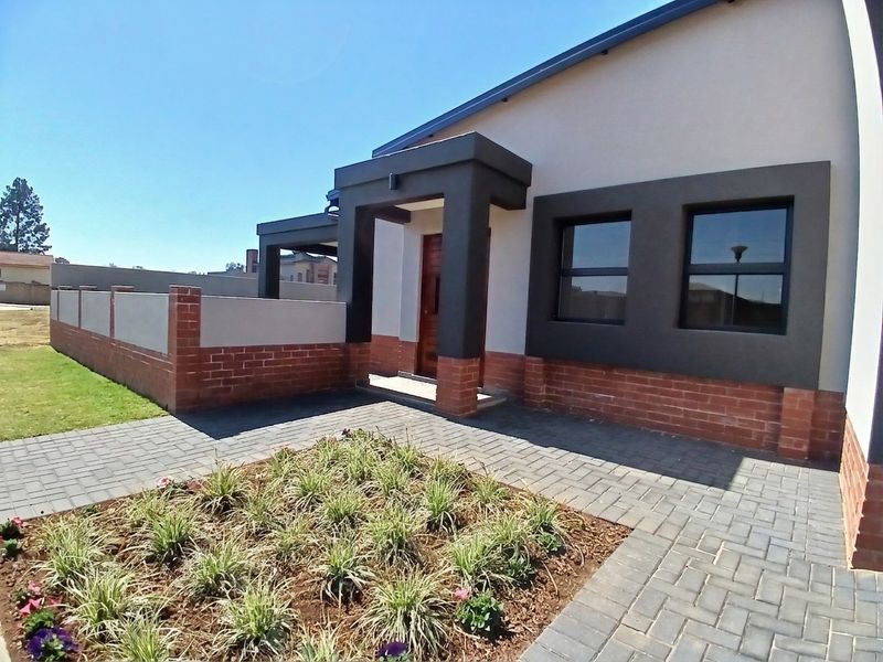 Modern front facade featuring a covered entrance, brick and plaster exterior finishes, paved walkway, and a landscaped garden bed.