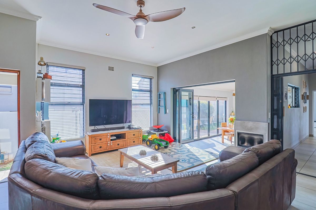 Spacious living room featuring a fireplace, ceiling fan, and large bi-fold doors that open to an outdoor patio area.