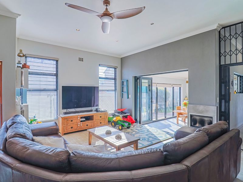 Spacious living room featuring a fireplace, ceiling fan, and large bi-fold doors that open to an outdoor patio area.