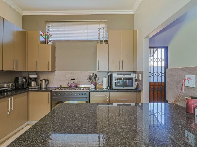 A functional kitchen featuring granite countertops, ample built-in cabinetry, a gas stove, and an oven, with direct access to an exterior security gate.