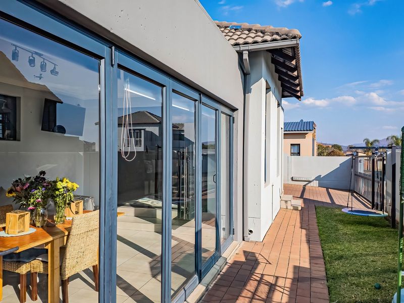 A well-maintained paved patio area featuring modern stacking glass doors that provide seamless access to the interior living space.