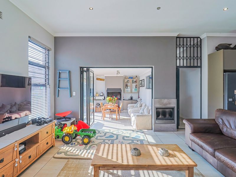Open-plan living area featuring tiled floors, a built-in fireplace, and bi-fold doors leading to an adjacent dining and patio space.