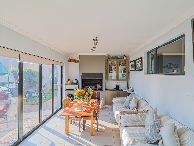 Enclosed patio area featuring a built-in braai, tiled flooring, and large sliding glass doors providing direct access to the garden.