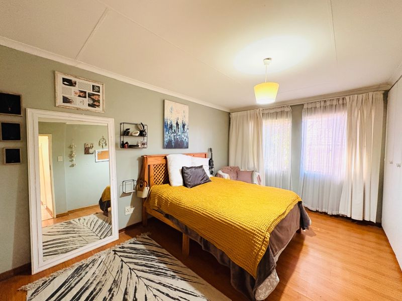 A well-lit bedroom featuring laminate flooring, neutral wall tones, and built-in wardrobe storage, offering a comfortable and functional living space.