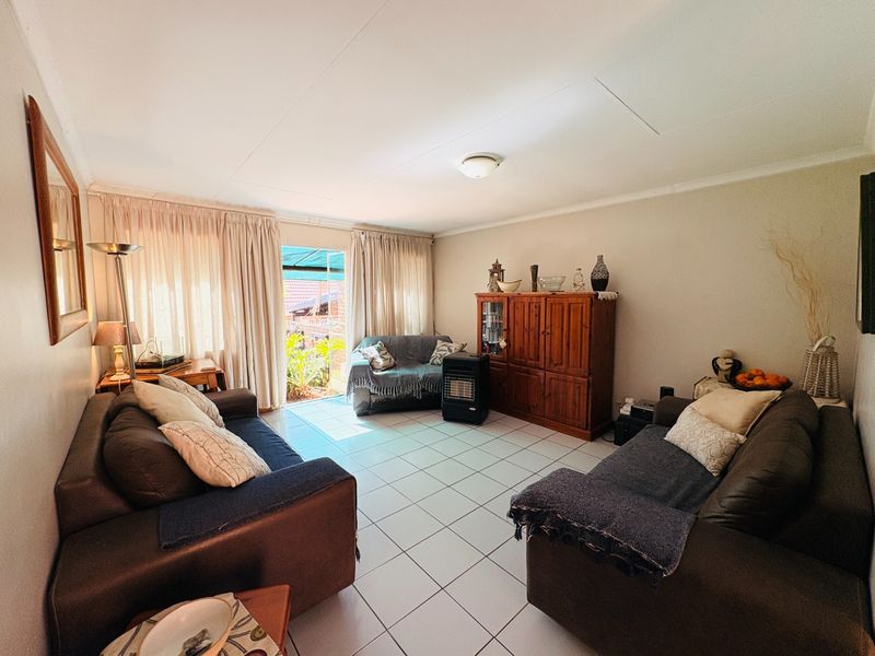 A living room featuring tiled flooring and a sliding glass door providing access to the outdoor area.