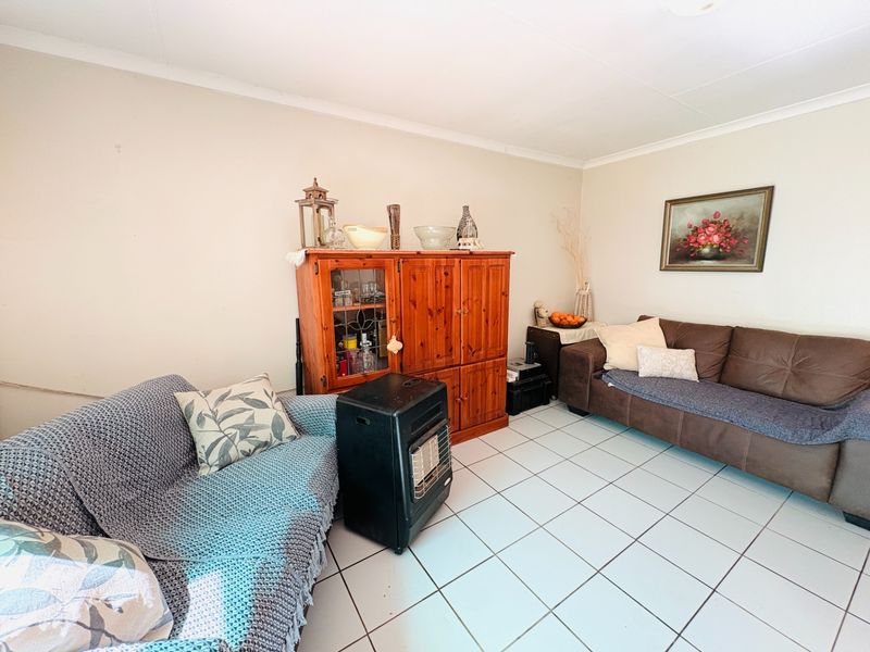 A living room area featuring neutral walls and tiled flooring, providing a functional space for relaxation.