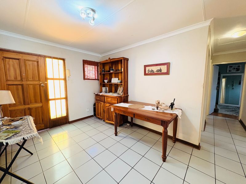 An entry area featuring tiled flooring, a timber front door with glass panels, and neutral wall finishes, providing access to the interior living spaces.