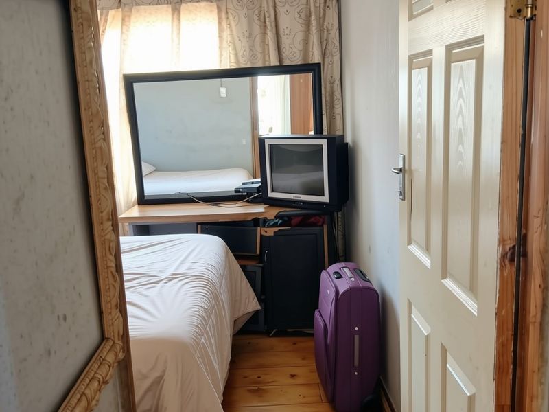 A compact bedroom featuring timber flooring and a standard panel door, currently utilized as a functional sleeping space.