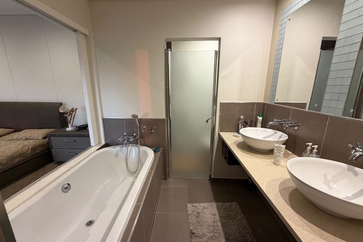 Modern bathroom featuring a double vanity with vessel sinks, a built-in bathtub, and a separate shower enclosure with a frosted glass door.