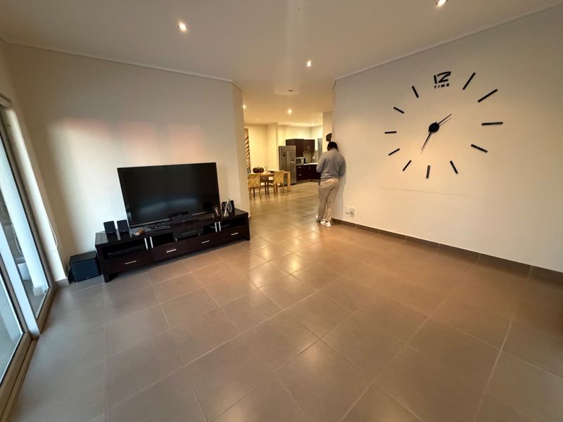 Spacious open-plan living area featuring neutral tiled flooring, recessed downlighting, and seamless flow into the adjacent kitchen and dining space.