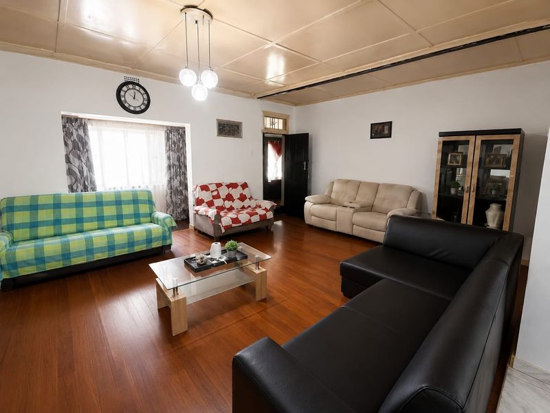 Spacious living room featuring warm hardwood flooring and a classic panelled ceiling, offering a comfortable and functional layout for family relaxation.