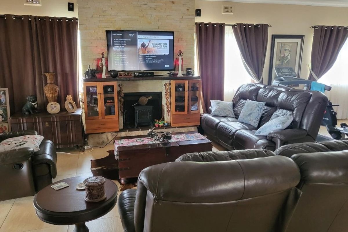 Spacious living room featuring a prominent stone fireplace with a built-in wood burning stove and integrated cabinetry, finished with neutral tiled flooring.