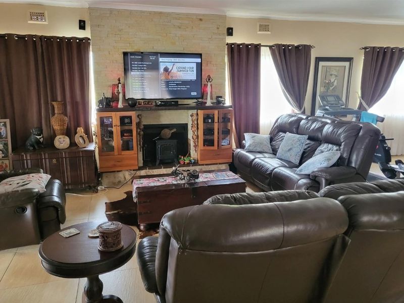 Spacious living room featuring a prominent stone fireplace with a built-in wood burning stove and integrated cabinetry, finished with neutral tiled flooring.