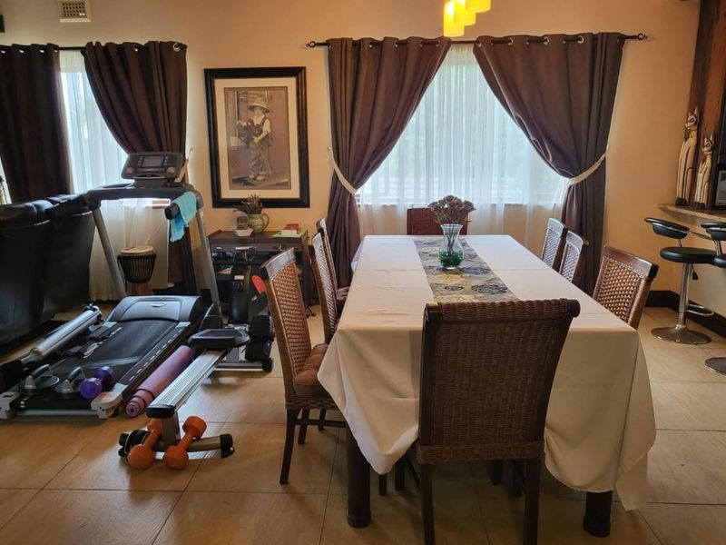 Open plan living and dining area featuring tiled flooring and a breakfast bar, currently utilized as a multi-purpose space.