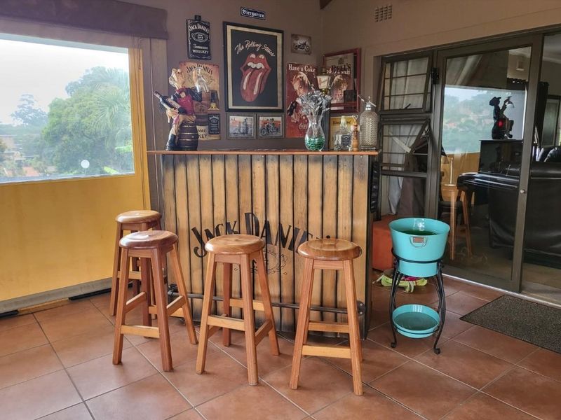 A dedicated bar area featuring a custom-built wooden bar counter, tiled flooring, and large sliding glass doors providing natural light and outdoor access.
