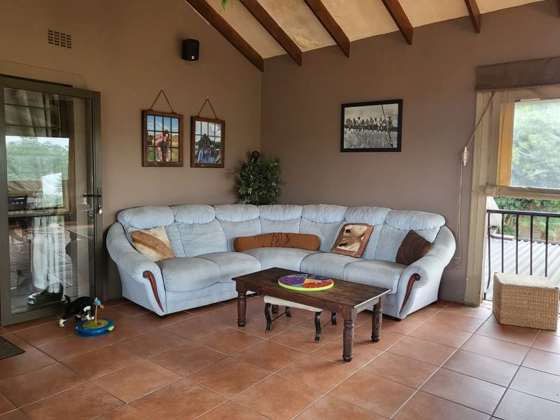 A covered patio area featuring exposed timber rafters, tiled flooring, and access to the outdoors through a sliding glass door.