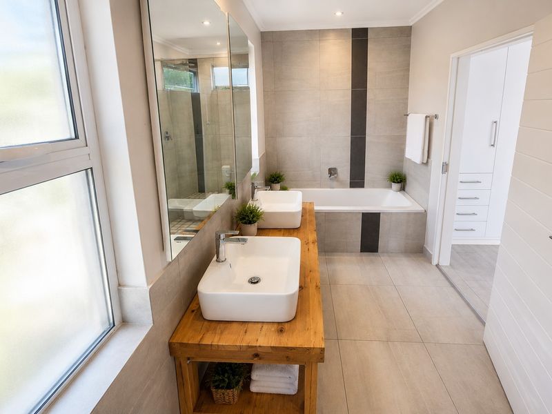Modern bathroom featuring a double vanity with vessel sinks, a built-in bathtub, neutral floor-to-ceiling tiling, and high-quality finishes.