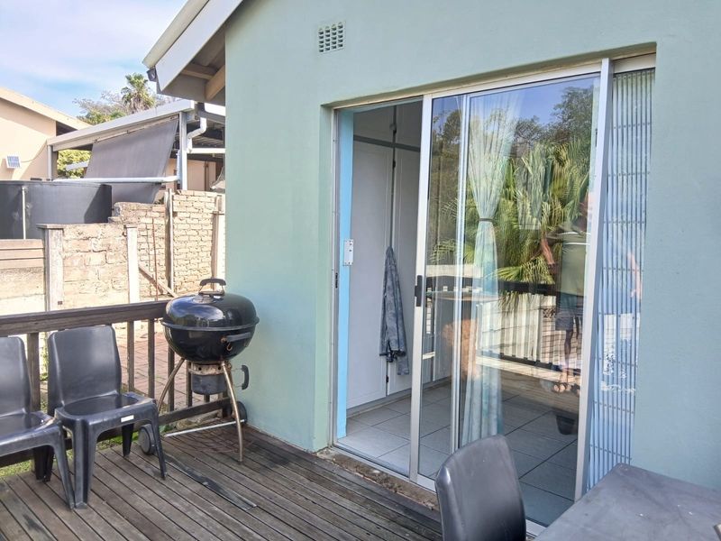 A timber deck patio area featuring a sliding glass door entrance, providing a functional outdoor space for relaxation and entertaining.