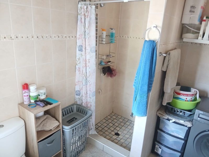 A functional bathroom featuring a tiled shower enclosure, standard toilet, and wall-mounted towel fixtures.