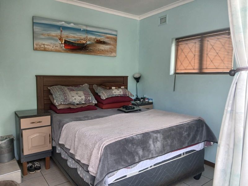 A functional bedroom featuring tiled flooring, a window with venetian blinds, and a ceiling ventilation unit.