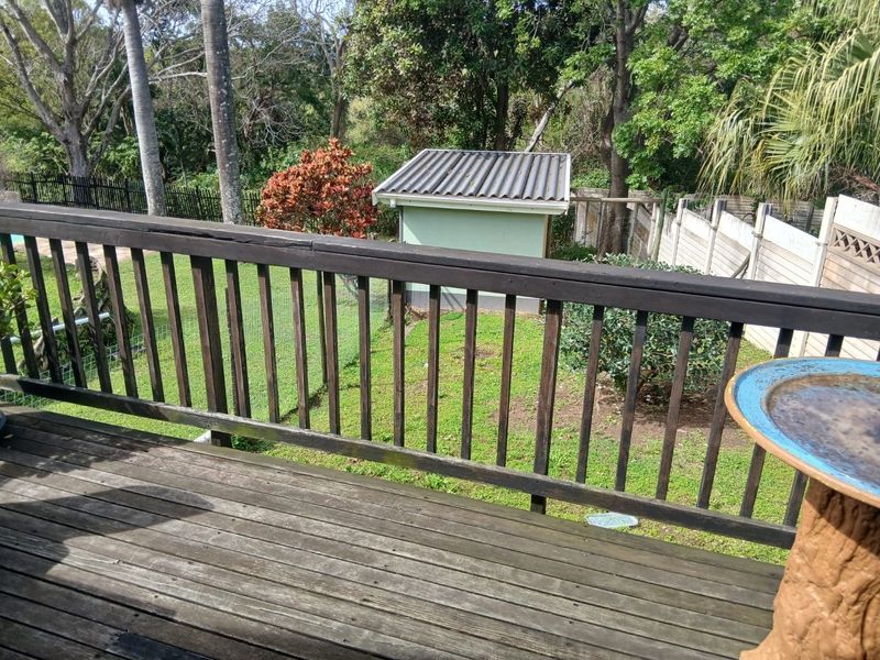 Elevated timber deck overlooking a private rear garden with a small storage shed and perimeter fencing.
