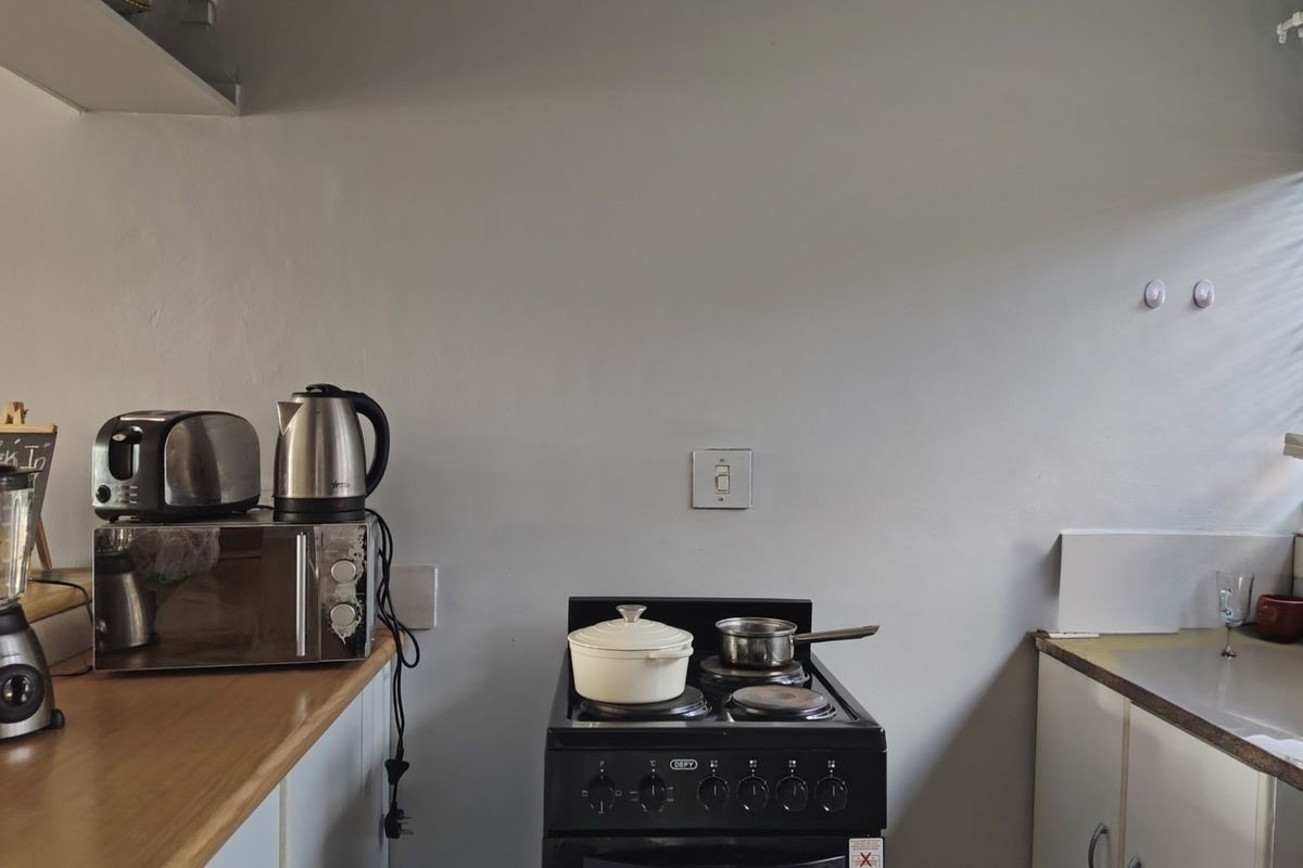 A functional kitchen area featuring a freestanding stove, laminate countertops, and built-in cabinetry with neutral wall finishes.