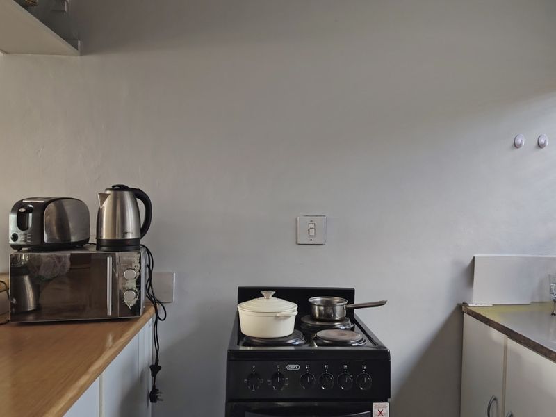 A functional kitchen area featuring a freestanding stove, laminate countertops, and built-in cabinetry with neutral wall finishes.