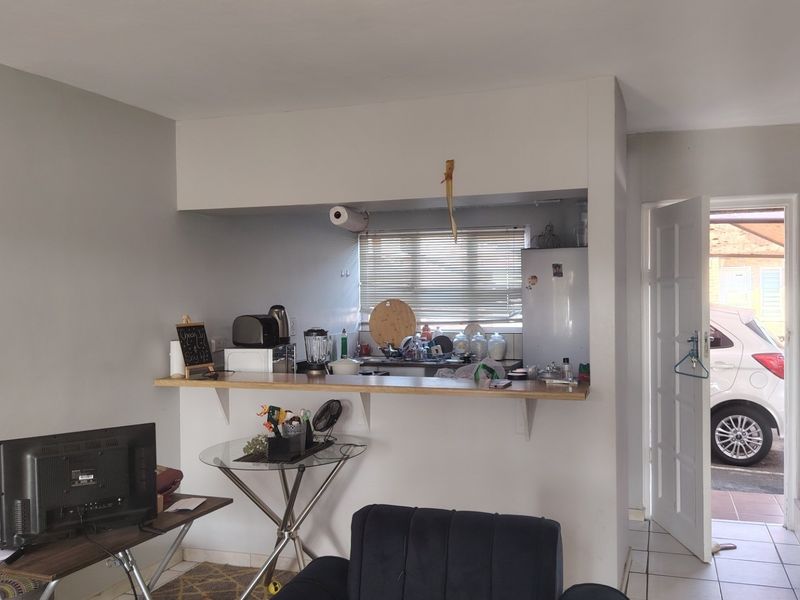Open plan living area featuring a breakfast bar, tiled flooring, and direct access to the exterior, with a staircase leading to the upper level.