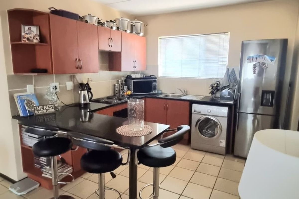 Functional kitchen featuring built-in cabinetry, laminate countertops, a breakfast bar, and tiled flooring with space for integrated appliances.
