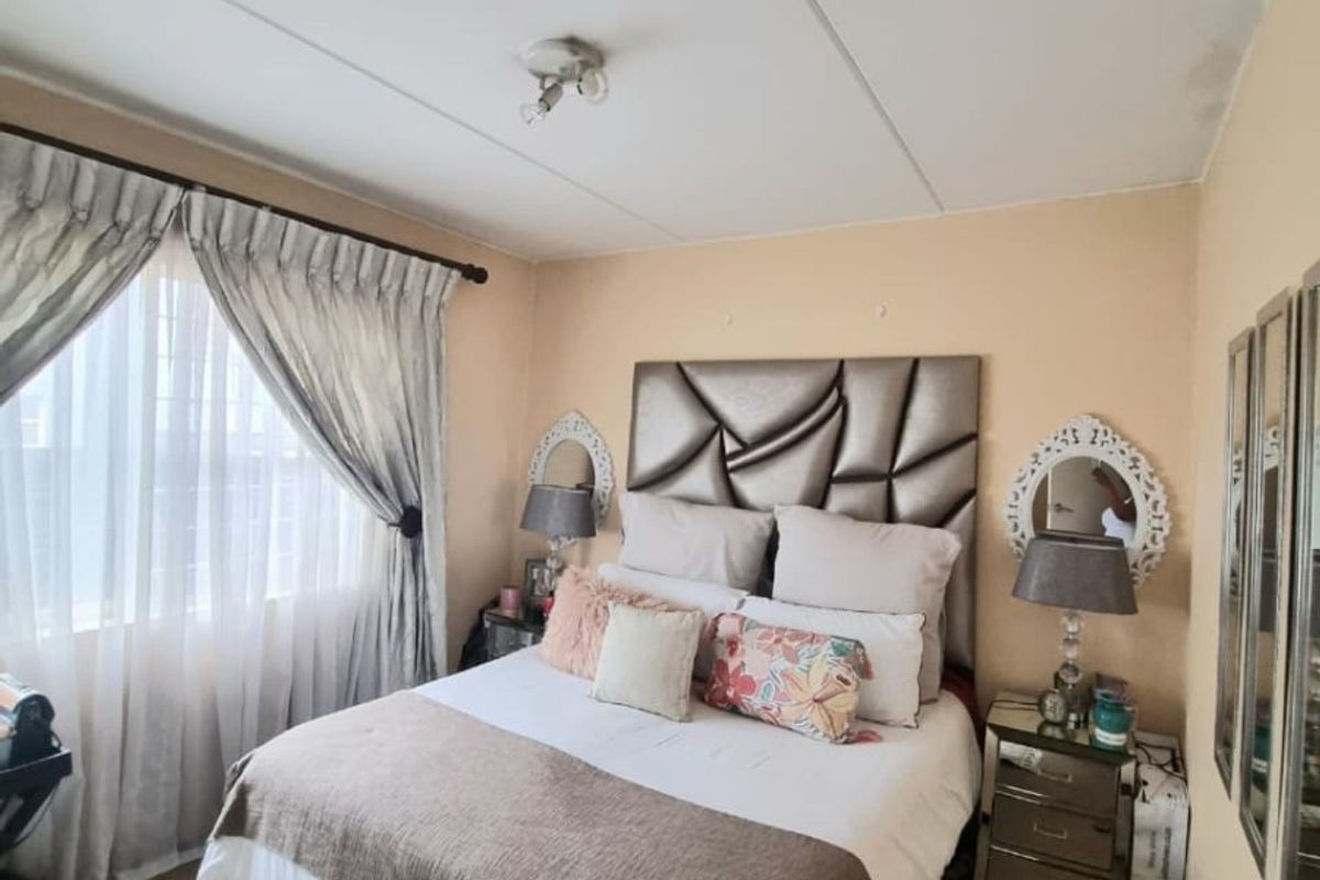 A cozy bedroom featuring neutral wall tones, carpeted flooring, and a window with installed curtain rails.